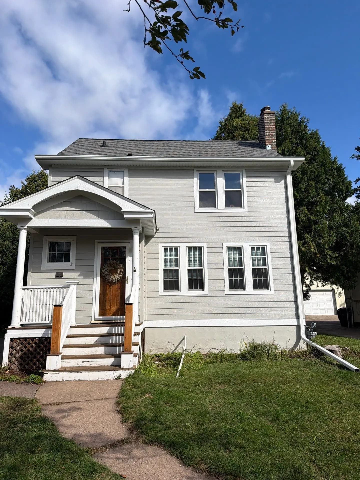 Two-story home in gray lap siding with white trim and a gabled front porch